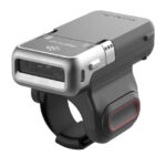 A Honeywell 8675i Wearable 2D Barcode Scanner mounted on a finger strap, featuring a compact, rugged design with a built-in scanner window. The device is designed for industrial and warehouse environments, offering hands-free barcode scanning with Bluetooth connectivity for enhanced productivity and ease of use.